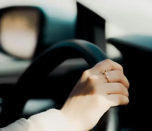 Person holding steering wheel wearing ring